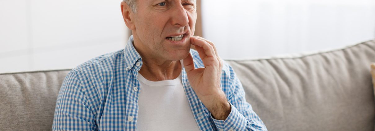 Portrait of unhappy mature man suffering from toothache